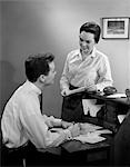 1960s COUPLE AT DESK GOING PAYING BILLS