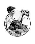 1930s BOY HOLDING UP TURKEY SURROUNDED BY TURKEYS