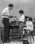 1920s FAMILY FATHER CARPENTER TEACHING SON AND DAUGHTER TO BUILD A BIRDHOUSE WITH WOODWORKING TOOLS