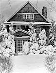 1940s THREE STORY HOUSE WITH PINE TREES AND SHRUBS COVERED WITH SNOW