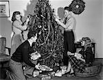 ANNÉES 1930 1940 METTANT D'ARBRE DE NOËL DÉCORATION FAMILLE ENVELOPPÉ DES CADEAUX SOUS L'ARBRE