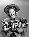 1940s WOMAN IN HAT HOLDING WRAPPED PRESENTS SMILING