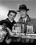 1950s SMILING PORTRAIT COUPLE IN WINTER COATS & HATS HOLDING WRAPPED GIFTS