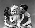 1930s MAN SMILING SANTA CLAUS POSING WITH BOY AND GIRL WHISPERING IN HIS EARS