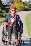 Femme en fauteuil roulant avec chien sur ses genoux