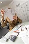 Frau Sortierung durch Rechnungen und e-Mail in einem Büro