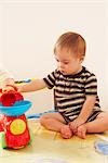 Garçon avec Down syndrome assis sur le plancher et jouer avec des jouets
