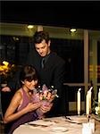 man giving woman flowers at dinner