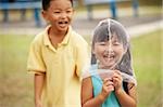 boy laughing at girl with butterfly net over her head