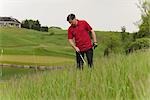 Homme à la recherche d'une balle perdue sur le parcours de Golf