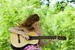 Young woman playing acoustic guitar outdoors