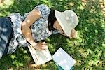 Young woman lying on the ground reading, high angle view