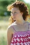 Young red haired woman outdoors, hair blowing in breeze, portrait