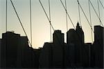 United States, New York City, silhouette of Manhattan skyline seen through Brooklyn Bridge