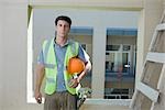 Construction worker holding hard hat under arm looking at camera