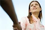 Young woman shaking man's hand, cropped, low angle view