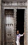 Jeune garçon à la recherche d'une porte arabe en bois sculptée traditionnelle à Stone Town, Zanzibar, Tanzanie, Afrique de l'est