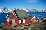 Maisons en bois sur la côte, avec les montagnes en arrière-plan, à Ammassalik, nord-est du Groenland, les régions polaires