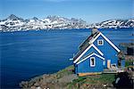 Maison en bois peint bleu sur la côte, avec les montagnes en arrière-plan, à Ammassalik, Groenland, les régions polaires
