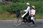 Two school girls in traditional Ao Dai on a bicycle in the Mekong Delta region south of Ho Chi Minh City in Vietnam, Indochina, Southeast Asia, Asia