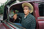 A man sitting in a 1950's American car, Pinar Del Rio Province, Cuba, West Indies, Caribbean, Central America