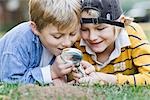 Little Boys Lying on Ground Holding Magnifying Glass