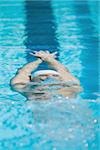 Young swimmer doing backstroke underwater