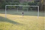 Garçon football botter le ballon de soccer au poteau de but
