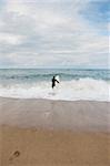 Man walking into the sea with surfboard