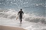 Young man running along shoreline with his surfboard