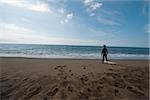 Jeune homme en combinaison debout sur la plage