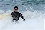 Jeune homme à l'intérieur de la mer avec sa planche de surf