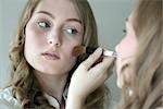 young woman putting on some make-up, portrait