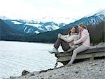 Two women sitting at lake