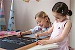 Two girls writing on blackboard