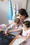 Mother and children writing on blackboard