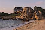 Beach house built behind rocks, Tregastel, Cote de Granit Rose, Cotes d'Armor, Brittany, France, Europe