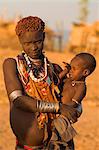 Karo woman with child wearing traditional goat skin dress decorated with cowie shells, Kolcho village, Lower Omo Valley, Ethiopia, Africa