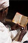 Old man wearing traditional gabi (white shawl) reading Holy Bible in rock-hewn monolithic church of Bet Medhane Alem (Saviour of the World), Lalibela, Ethiopia, Africa