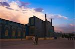 Menschen gehen bei Sonnenuntergang hinter dem Schrein von Hazrat Ali, der ermordet wurde 661, Mazar-i-Sharif, Afghanistan, Asien