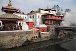 Smoke rising from cremation ceremony on banks of Bagmati River during Shivaratri festival, Pashupatinath Temple, UNESCO World Heritage Site, Kathmandu, Nepal, Asia