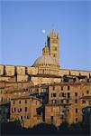 Moon in the sky above cathedral and houses clustered below at sunset, Siena, Tuscany, Italy, Europe