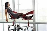Professionelle Frau ihre Beine bis auf Bürostuhl ruht