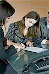 Young woman signing document, professional woman pointing