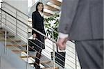 Businessman walking up to businesswoman on staircase
