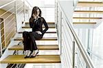 Businesswoman talking on cell phone on office staircase