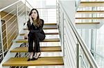 Businesswoman talking on cell phone on office staircase