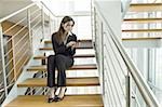 Businesswoman telephoning from cell phone on office staircase