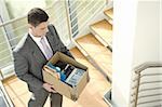 Businessman on office staircase with box of belongings