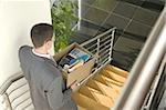 Businessman on office staircase with box of belongings